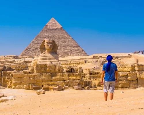 A young man walking towards the Great Sphinx of Giza and in the background the pyramid of Khafre,