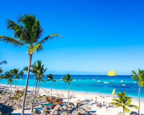 Aerial view of Bavaro beach Punta Cana tropical resort in Dominican Republic. Beautiful atlantic tropical beach with palms, umbrellas and parasailing balloon.