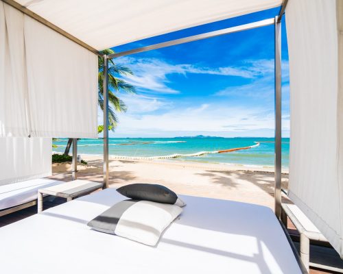 Outdoor deck with pillow neary beach and sea with coconut palm tree on blue sky background