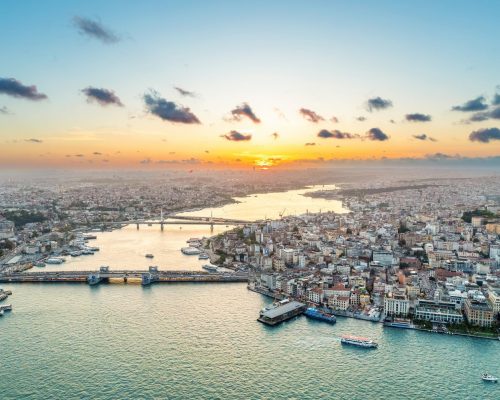 Aerial drone view of Istanbul at sunset, Turkey. Multiple residential buildings, mosques, Galata and Metro bridges over the Golden Horn waterway with floating ships